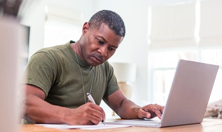 Serious mature adult soldier takes continuing education courses online using his laptop.