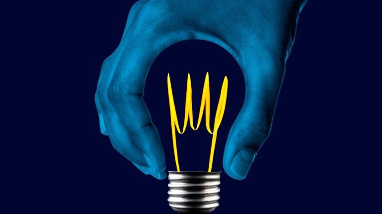 A thumb and an index finger form a circular void, resembling the shape of a light bulb but without the glass component. Inside this empty space, a bright filament and the gleaming metal base of the light bulb are visible.