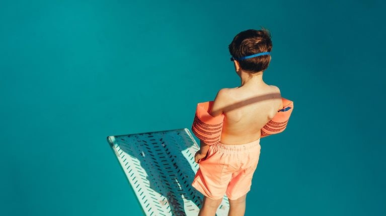 Boy standing on a diving board - stock photo