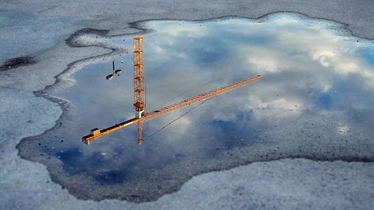 Reflection of a crane tower in a puddle