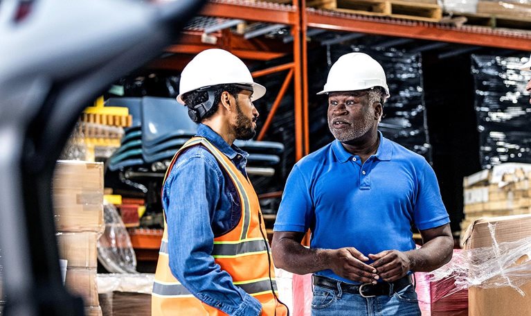 Warehouse supervisor speaking with a group of employees