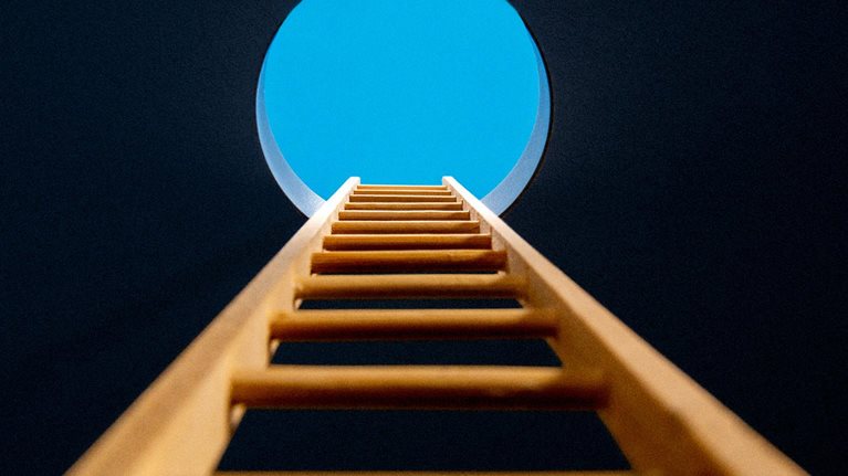 Point of view, looking up ladder sticking through hole in ceiling revealing blue sky