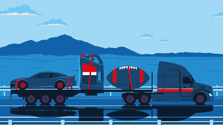 A semi-truck is shown driving on a highway with symbols on its flatbed that represent the life and legacy of Lucas oil founder, Forrest Lucas. A car, a bottle of synthetic oil, and a large American football are set against a scenic backdrop of mountains and a blue sky with clouds.