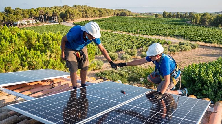 Two workers installing solar panels - stock photo