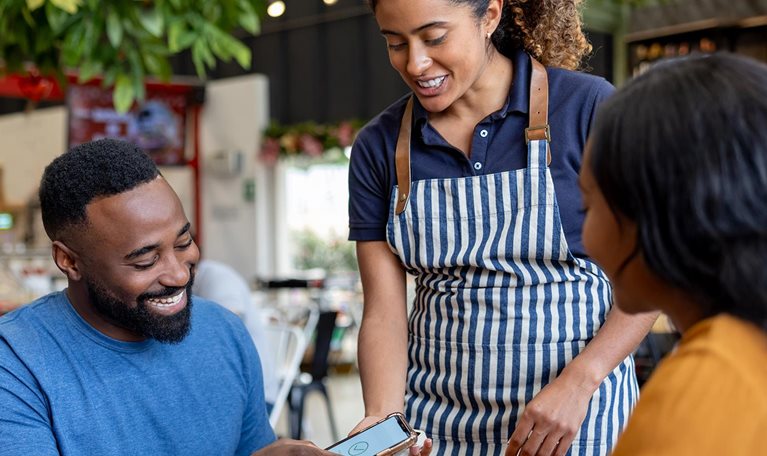 Man on a date making a mobile payment to the waitress at a coffee shop