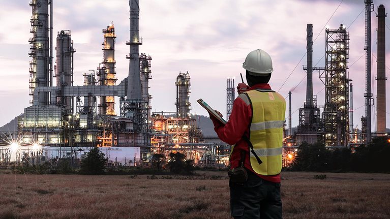 The image shows an engineer or safety professional at a petrochemical or industrial plant.