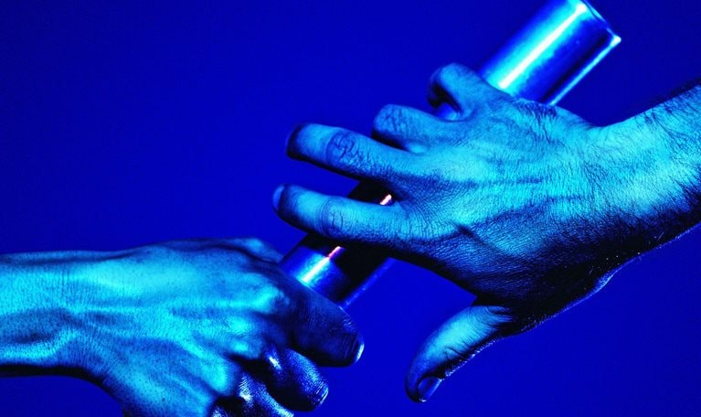 One hand passing a baton to the other