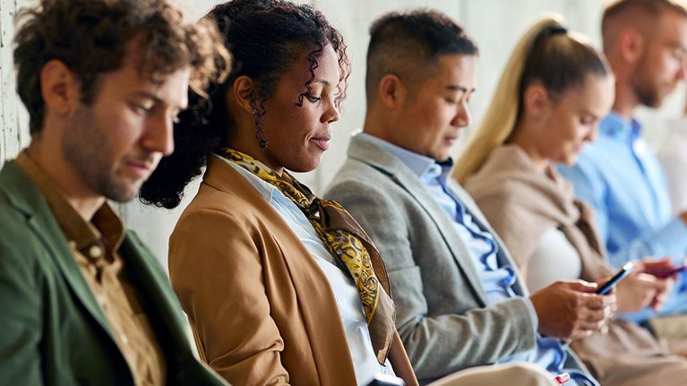 Large group of business people waiting for a job interview in a hallway.