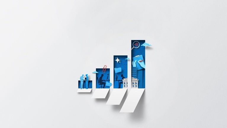 A white sheet of paper has been cut creating the silhouette of a bar graph showing upward growth. The interior of each bar is filled with dynamic blue and red shapes representing business and productivity, including teamwork, technology, and growth.