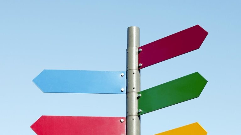 A signpost with arrow shaped signs of different colors pointing in different directions.