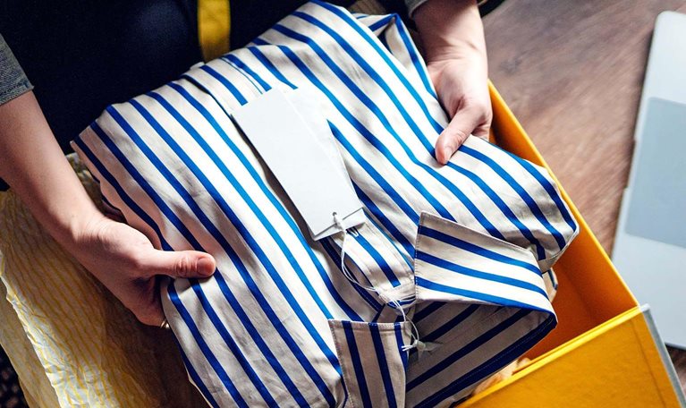 Elevated view of young woman unboxing a delivery from home shopping, with a laptop by her side.