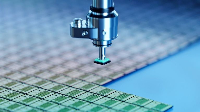 Close-up of semiconductor packaging process. Computer chips are being extracted by a pick and place machine from wafer and attached to substrate.