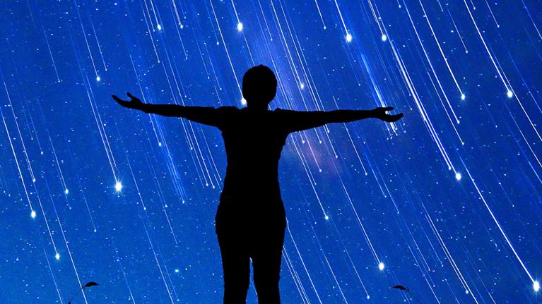  A girl standing with her arms open to a sky full of shooting stars