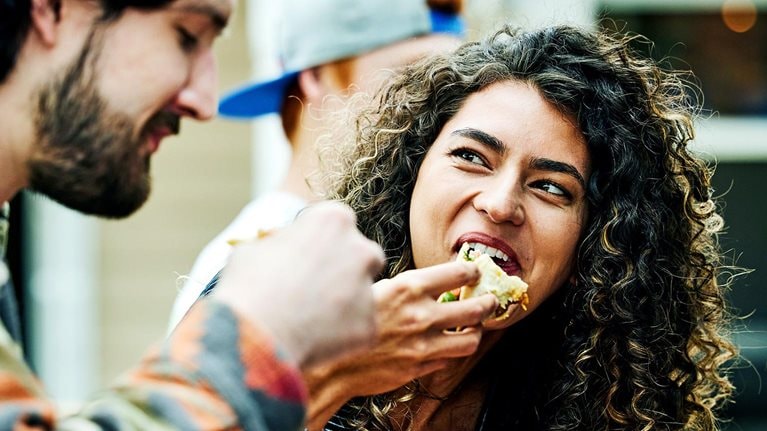 Medium close up shot of woman eating tacos with friends at food truck
