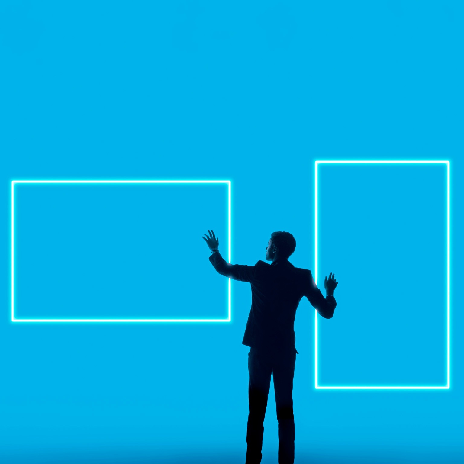 A silhouetted man in a suit stands against a bright blue background, reaching toward two glowing rectangular outlines that resemble digital screens or frames.