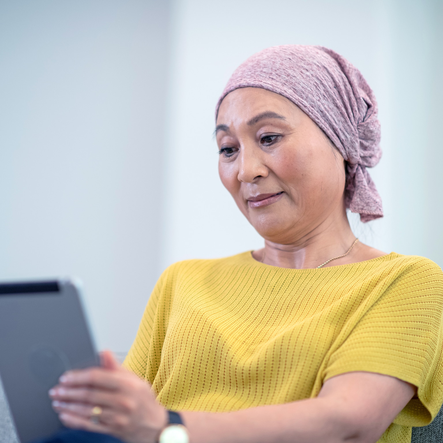Woman in yellow reading on a tab