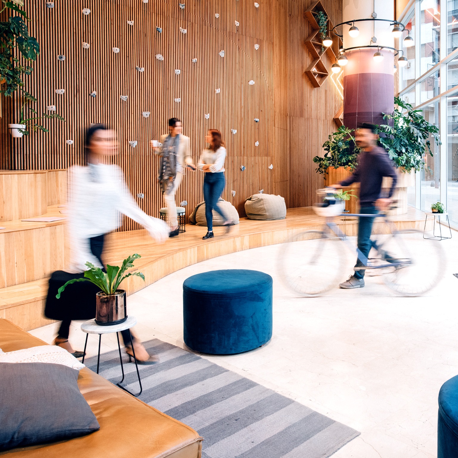 A building's reception, where people are engaged in many activities. A grayed out cycle and walkers are seen in the enclosure showing flexibility in the workplace.