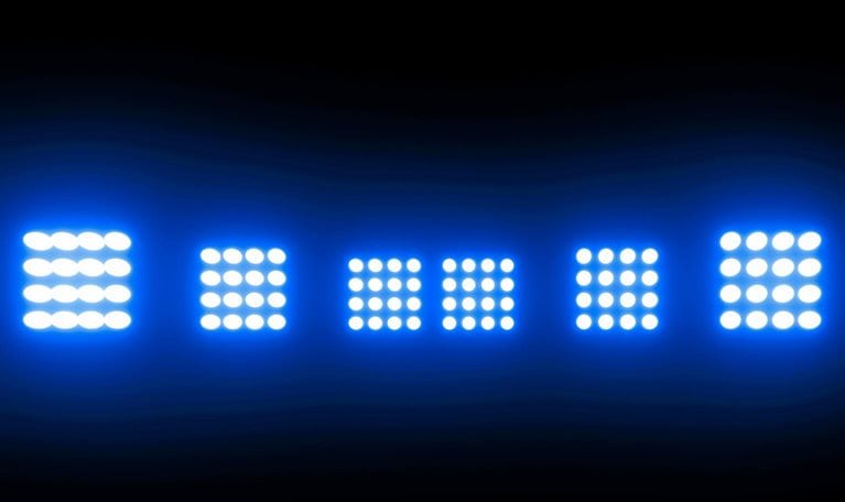 A row of five bright, white LED stadium lights are positioned against a dark blue backdrop.