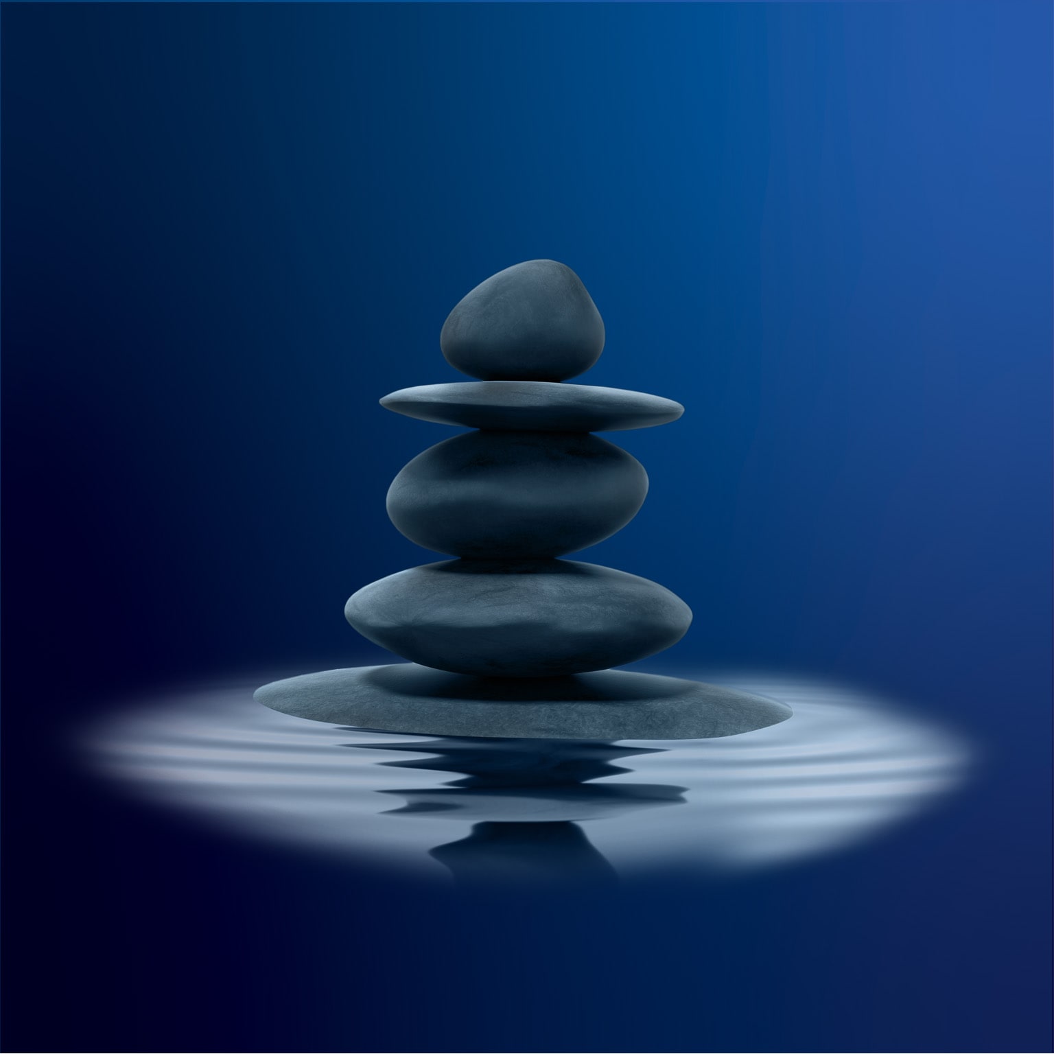 Stacked black zen stones in shallow water
