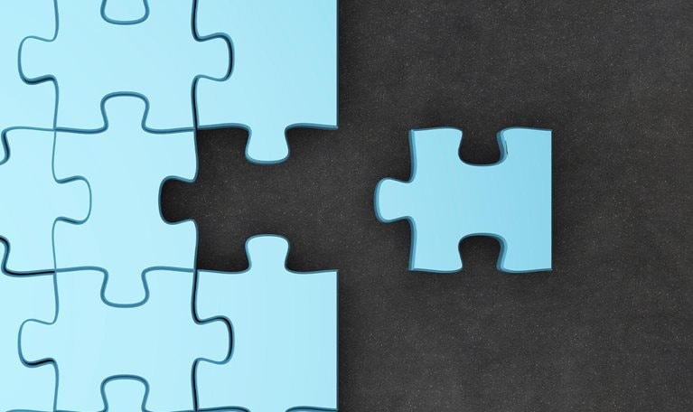 Jigsaw puzzle pieces. One fitting piece sitting outside of nearly completed puzzle.