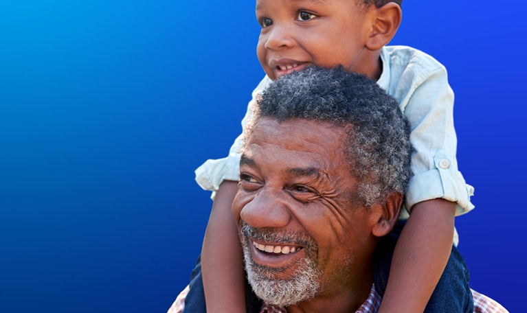 Grandfather carries grandson on shoulders during walk in park