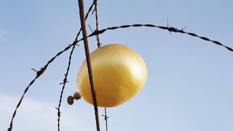 Deflating golden balloon caught in barbed wire