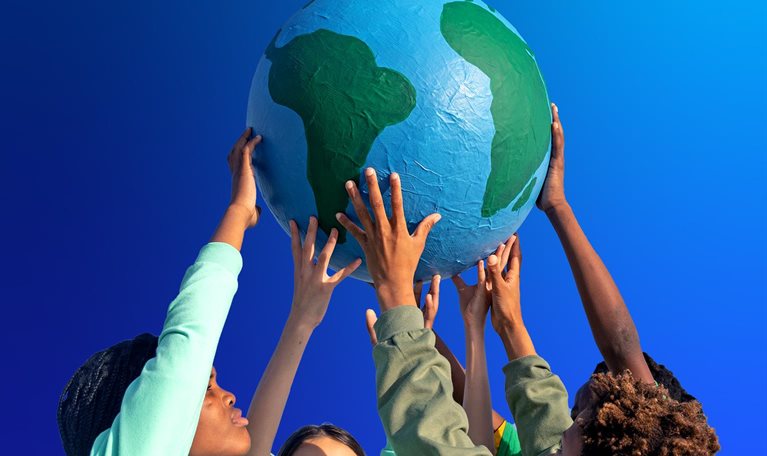 Group of children working together to hold up the world - stock photo