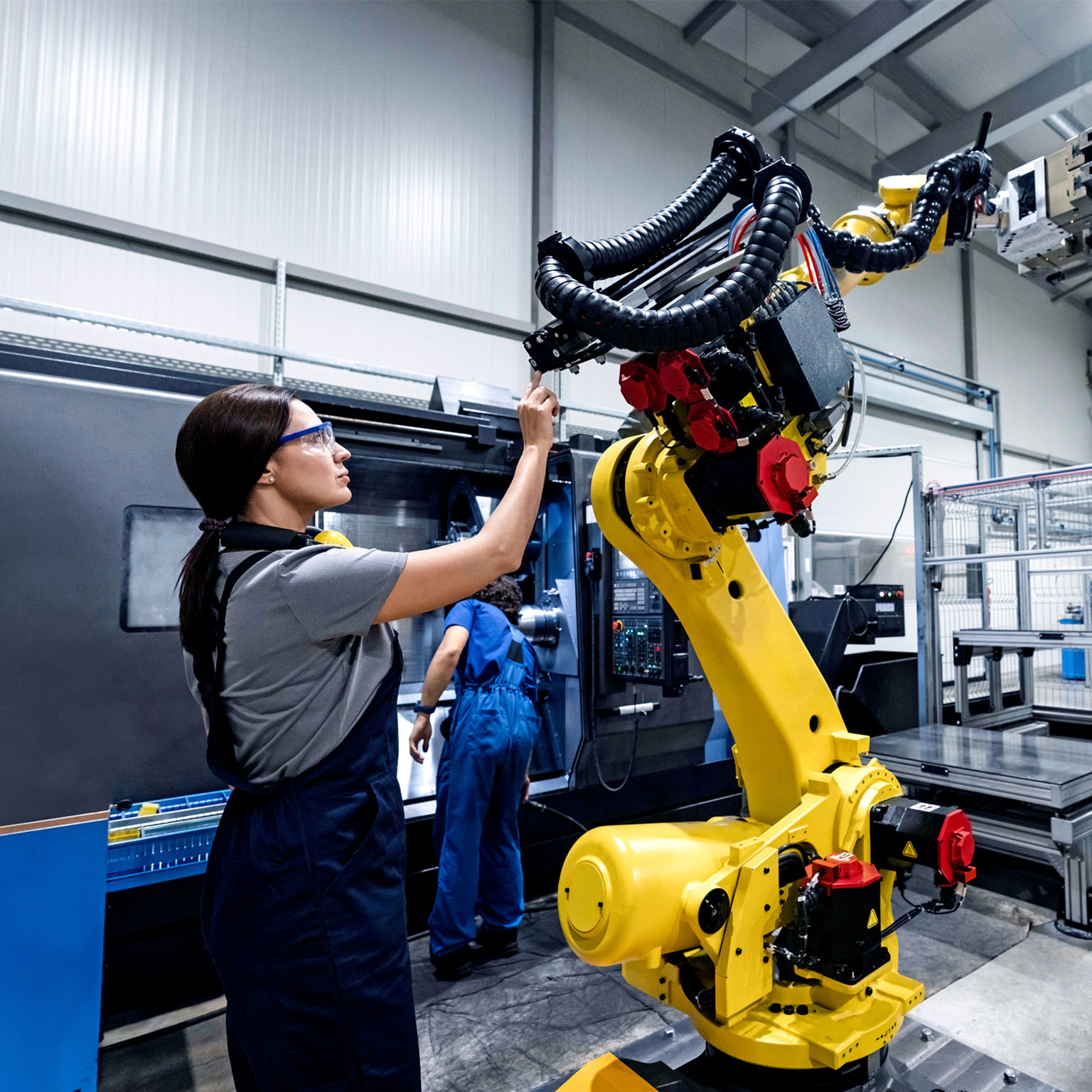 Maintenance engineer working in a factory using robotic arm