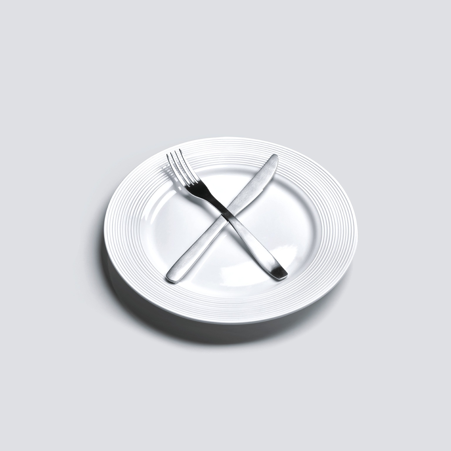 Empty plate with knife and fork in cross shape