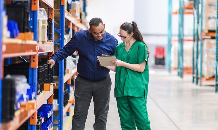 Warehouse workers managing medical inventory in organized storage facility with modern equipment.