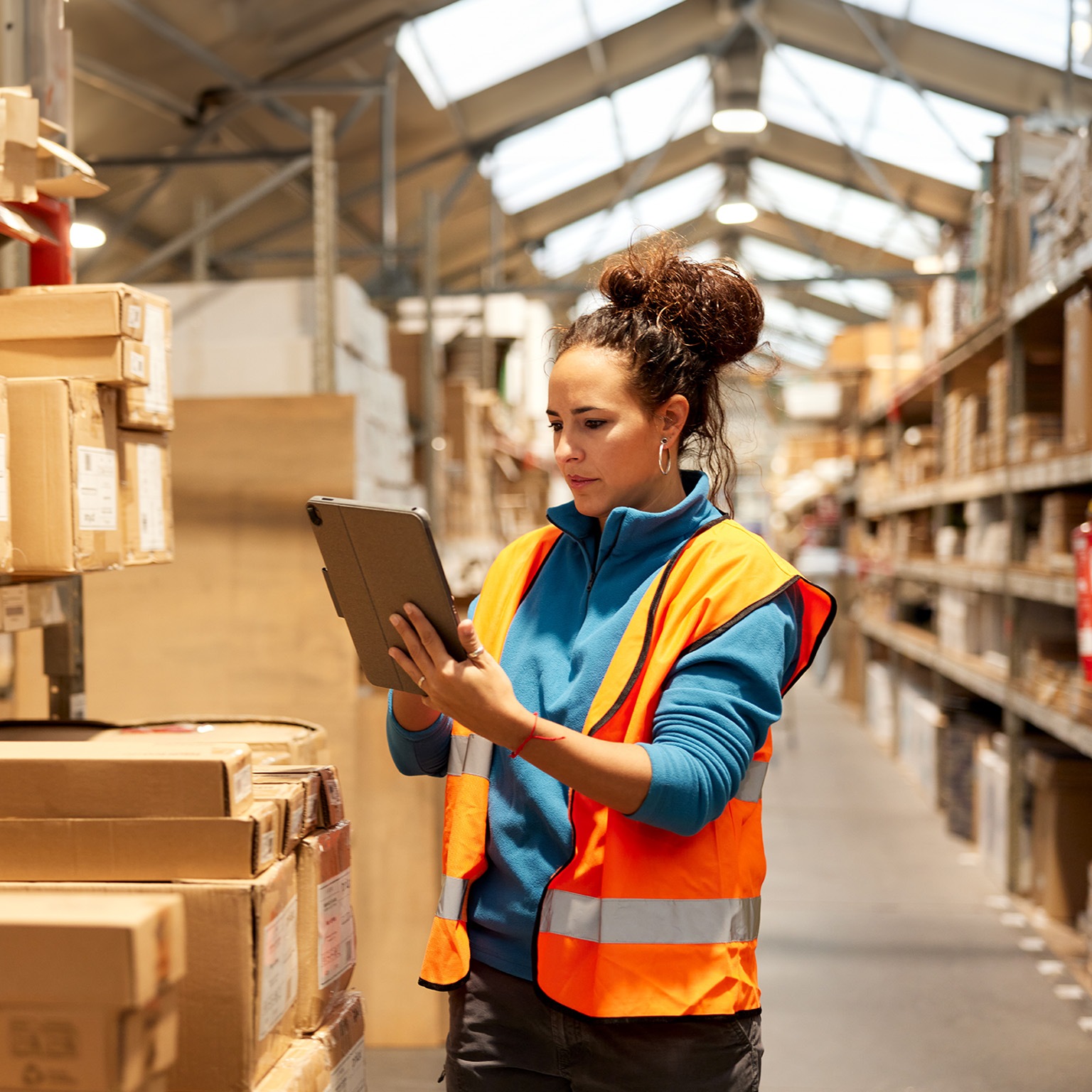 A warehouse worker takes inventory in the storage room standing next to a shelf and using a digital tablet. - stock photo