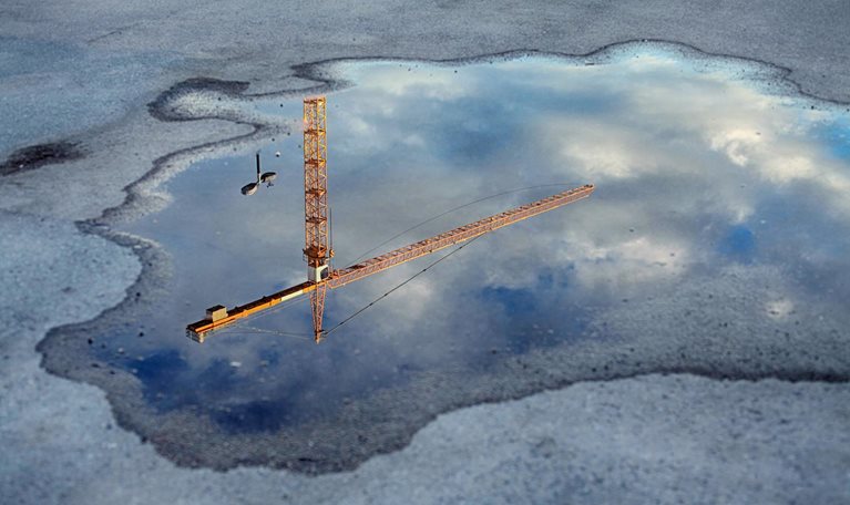 Reflection of a crane tower in a puddle