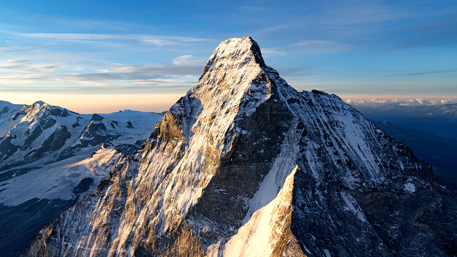 A snow covered mountain peak against a blue sky.