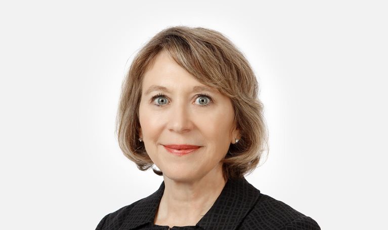 Portrait of a smiling Jayne Plunkett against a white backdrop.