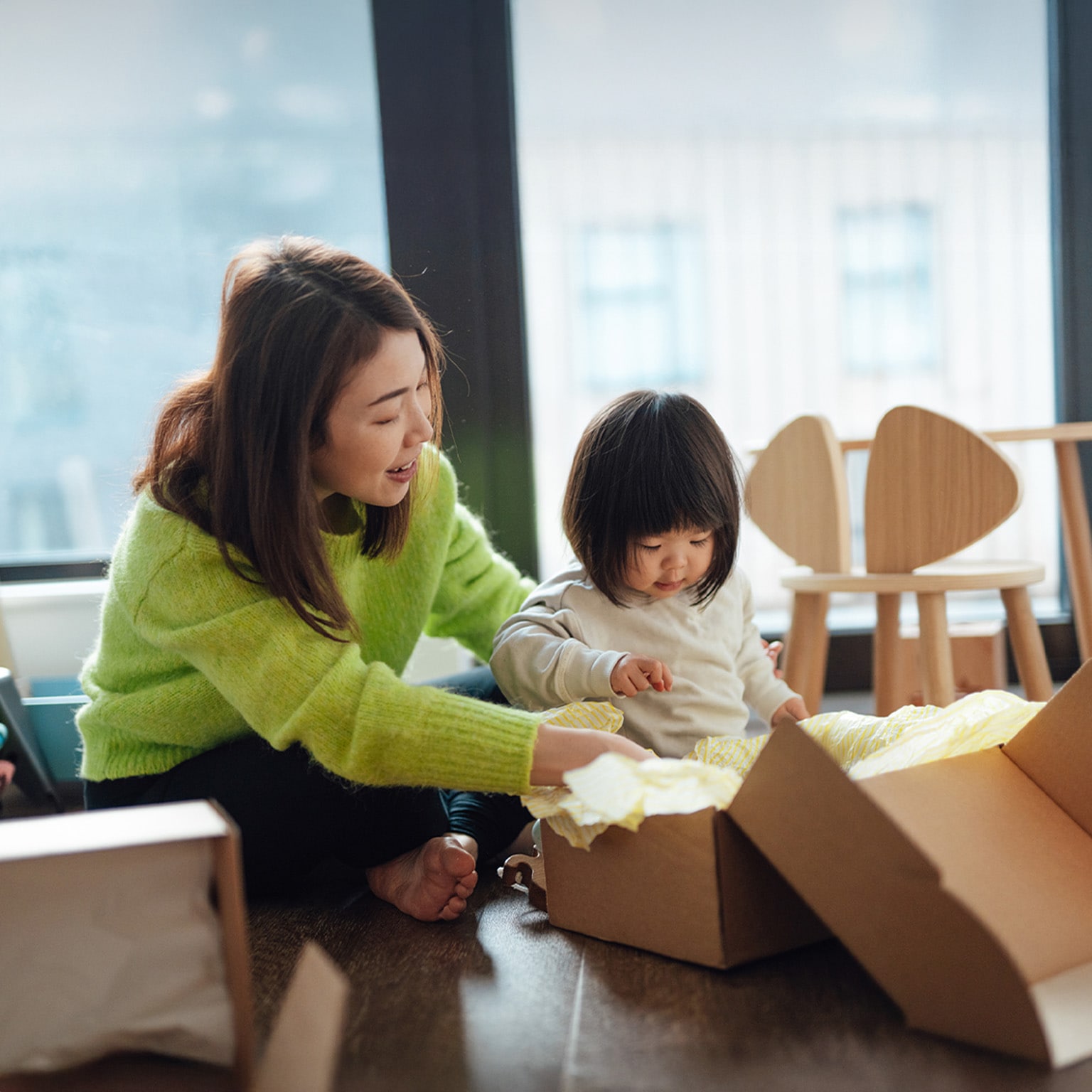 Young Asian mother unpacking parcel from online shopping with her toddler