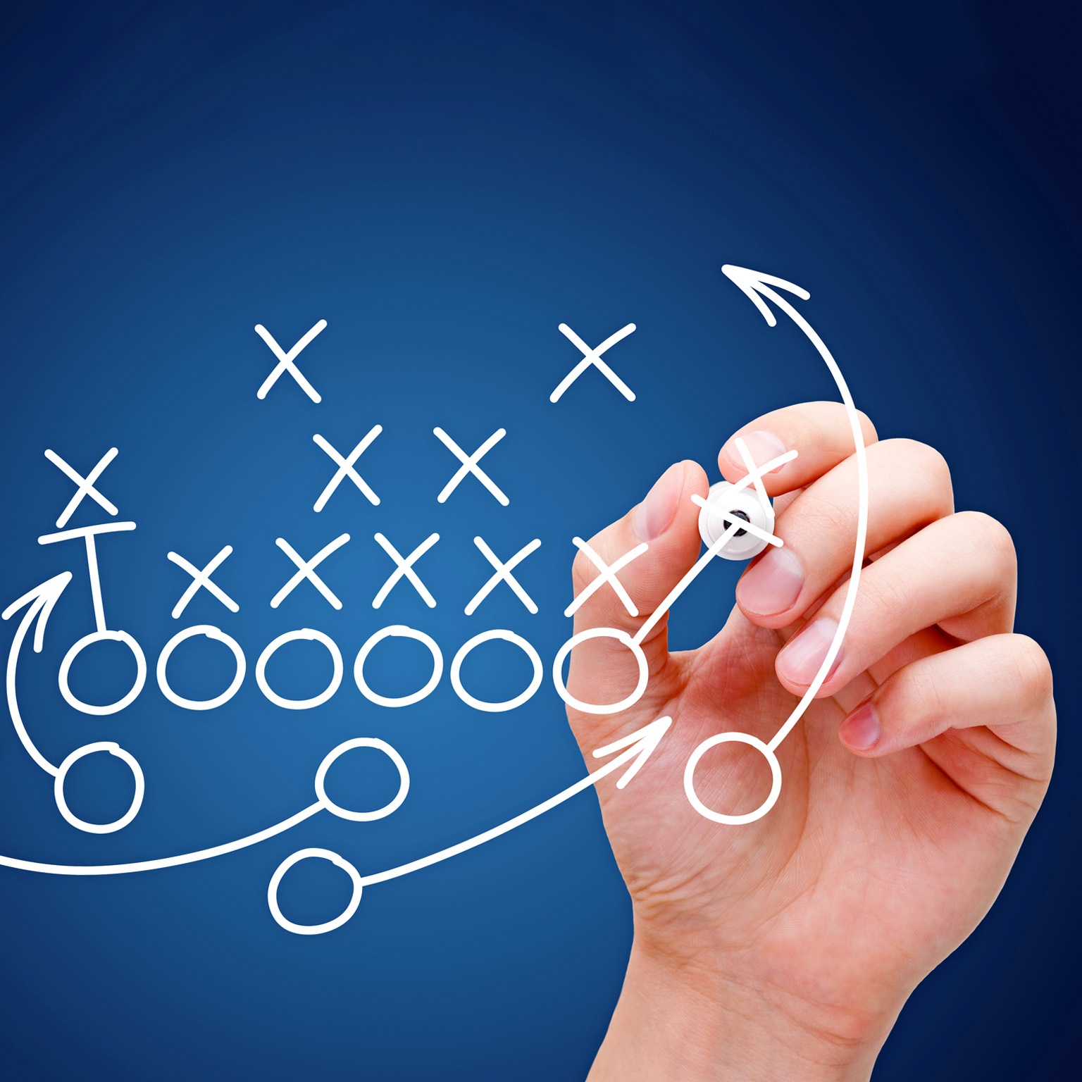 A football play diagram is being sketched by a hand, featuring Xs and Os to represent players and arrows indicating their movements.