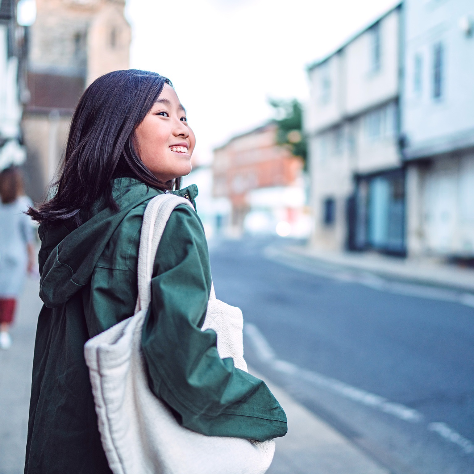Cheerful teenage girl walking in the street while exploring in a town