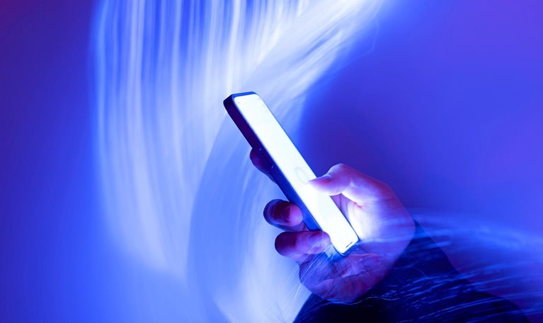Close-up of using mobile phone on holographic background