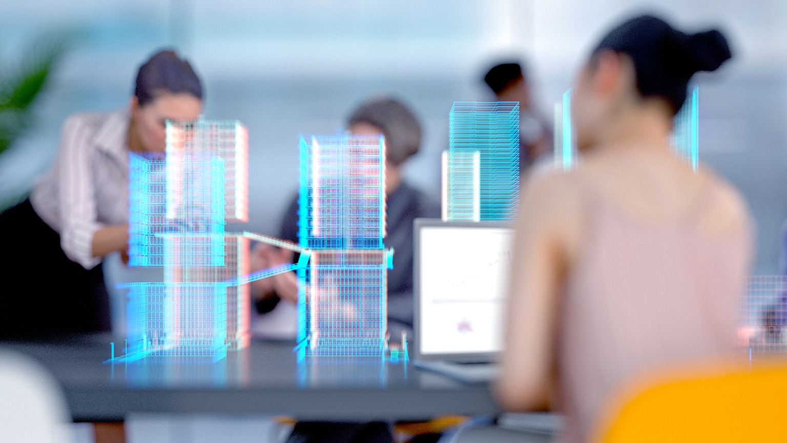 Team collaborating at a table with digital holographic models of buildings displayed in front of them.