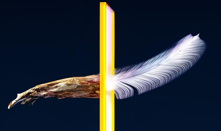 A wooden object going through a luminous yellow gateway and changing into a feather upon emerging.