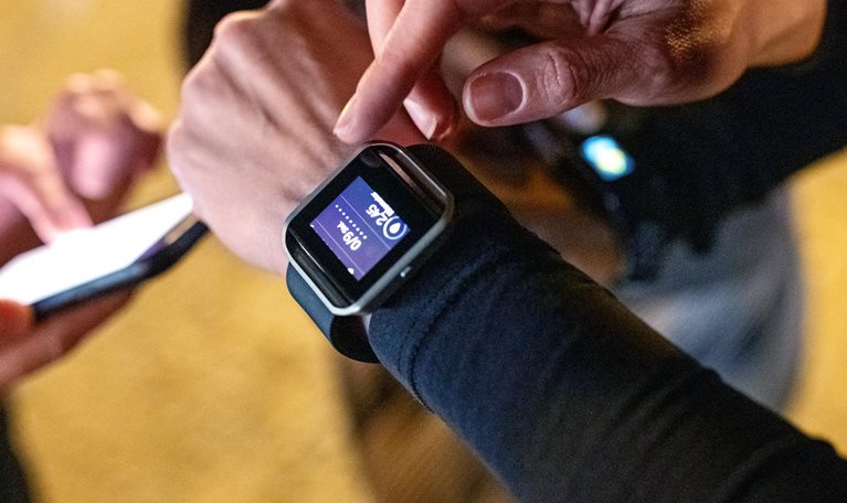 Close-up of young people standing together using their smart devices after a workout session.