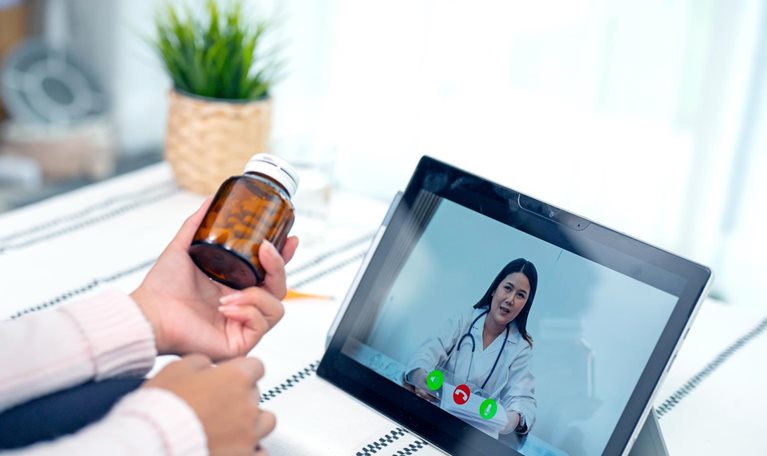 A young woman engaged in a video conference with her doctor.