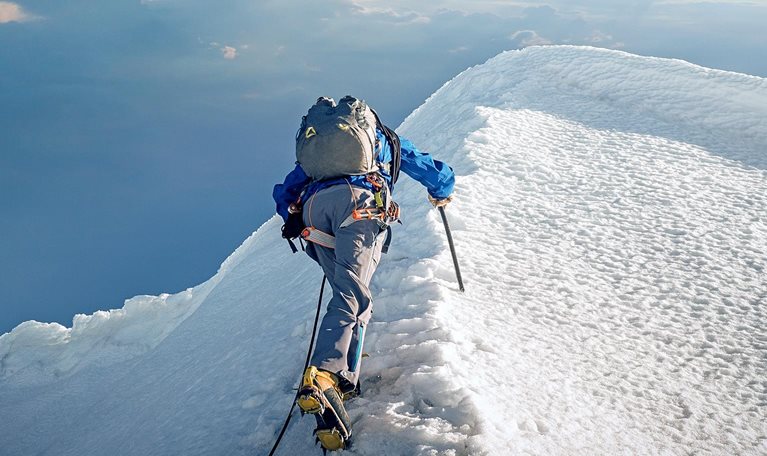 A lone climber ascending a snowy ridge in the Alps