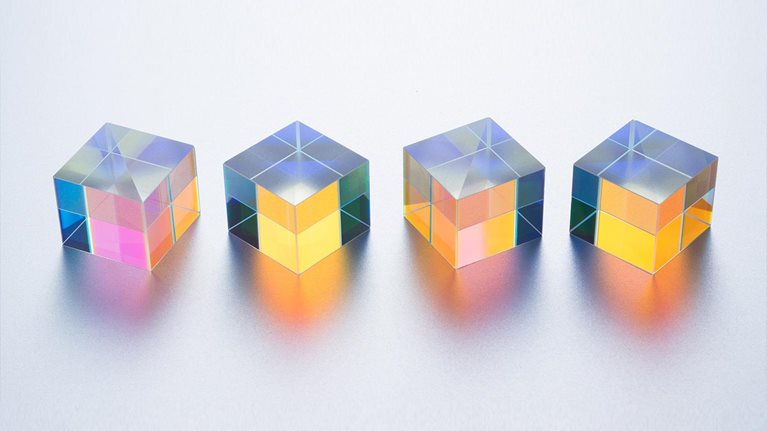 Four X-cube Prisms in a Row on Silver Background Close-up View - stock photo