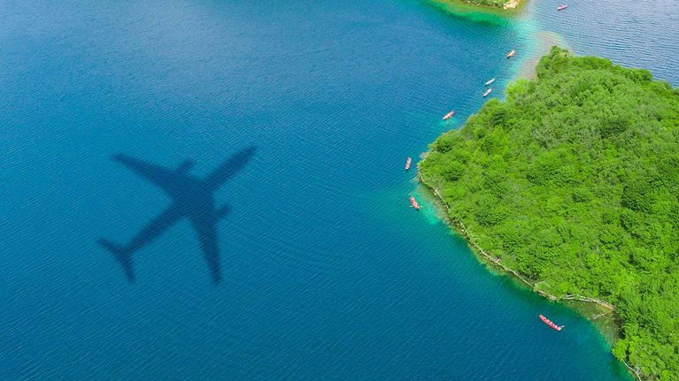 Airplane shadow over the island forest - stock photo