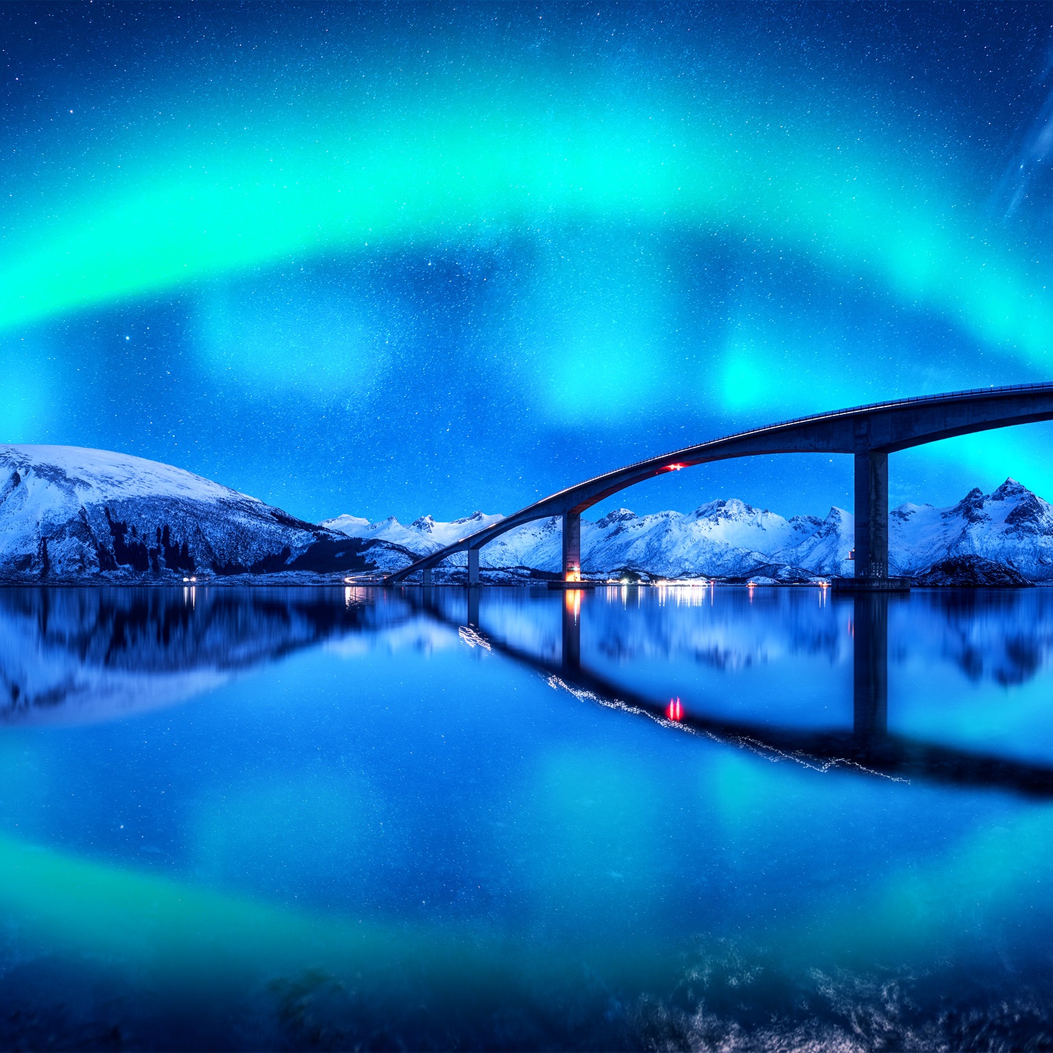 A Bridge and aurora borealis over snowy mountains