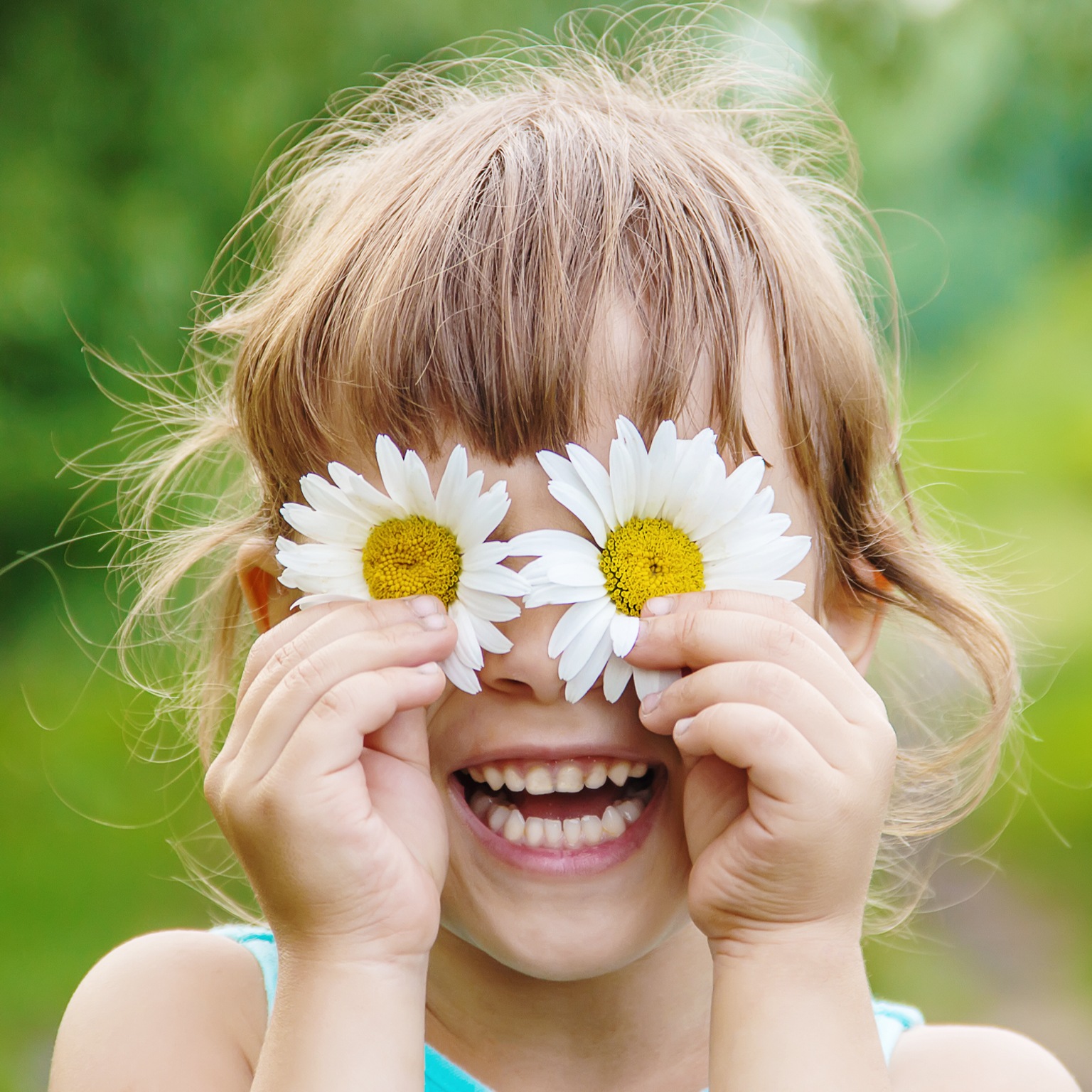 The girl is holding chamomile flowers in her hands