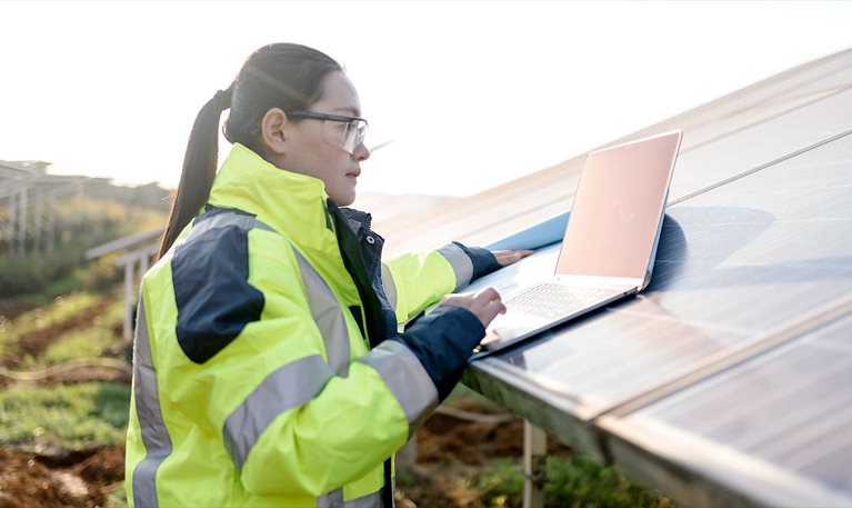 Worker with laptop adjusting solar panels