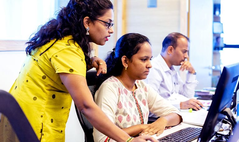 An office Manager training colleague using a Desktop Computer