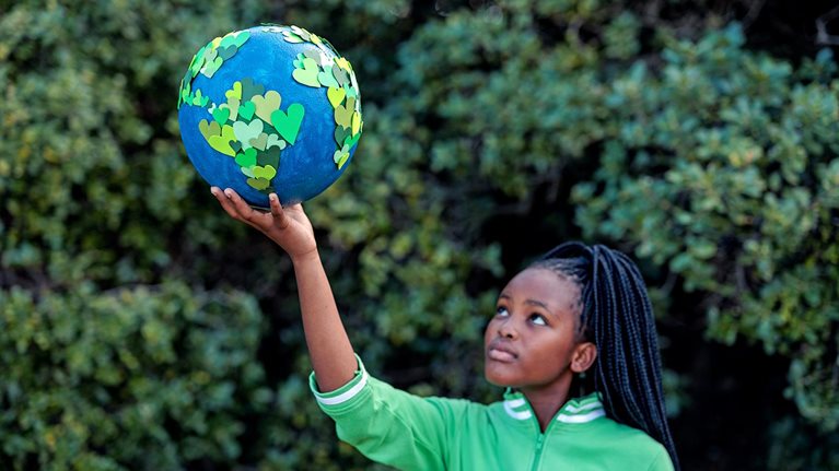 Young African girl holding up a homemade globe of green heart shapes
